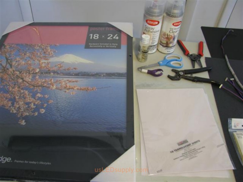 Poster frame, scissors, adhesive, transluscent paper for making LED silhouette art project.