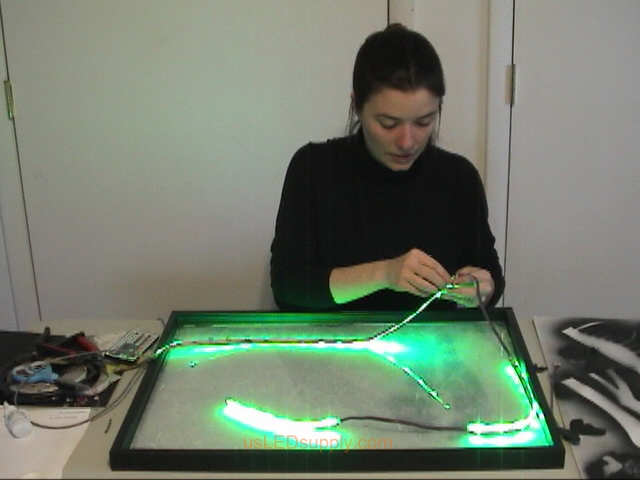Attach RGB flexible LED strips to the bottom edge of the poster frame and on the glass behind the couple.