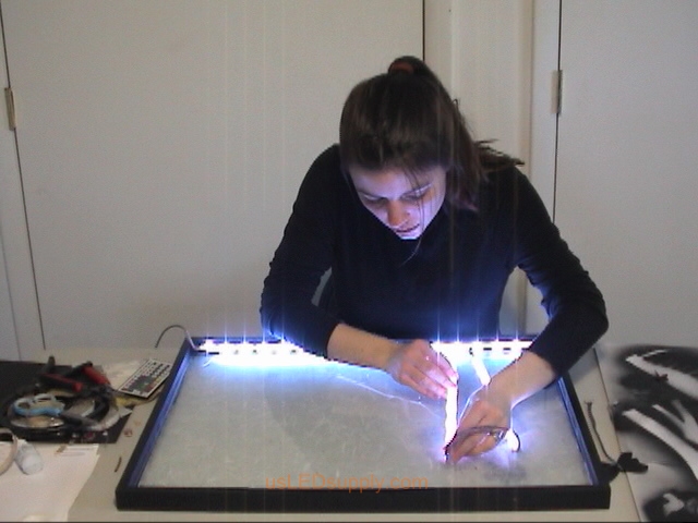 Attach RGB flexible LED strips to the bottom edge of the poster frame and on the glass behind the couple.