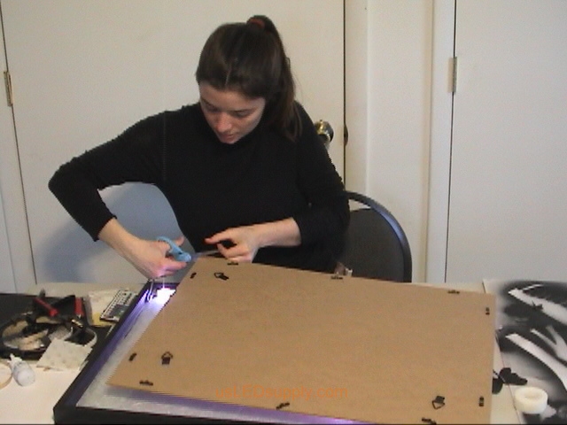 Cut small opening in the bottom corner of the backing for the frame, enough for the power cable to fit through.
