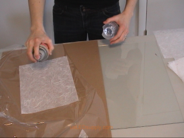 Use spray adhesive or gluestick to attach transluscent paper to glass.