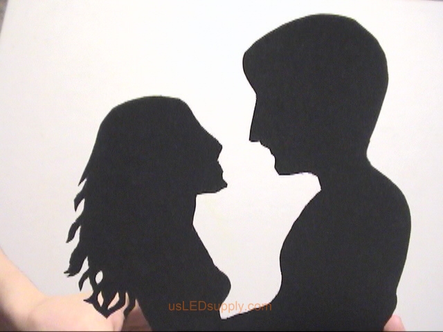 Couple heads cut out of black poster paper.