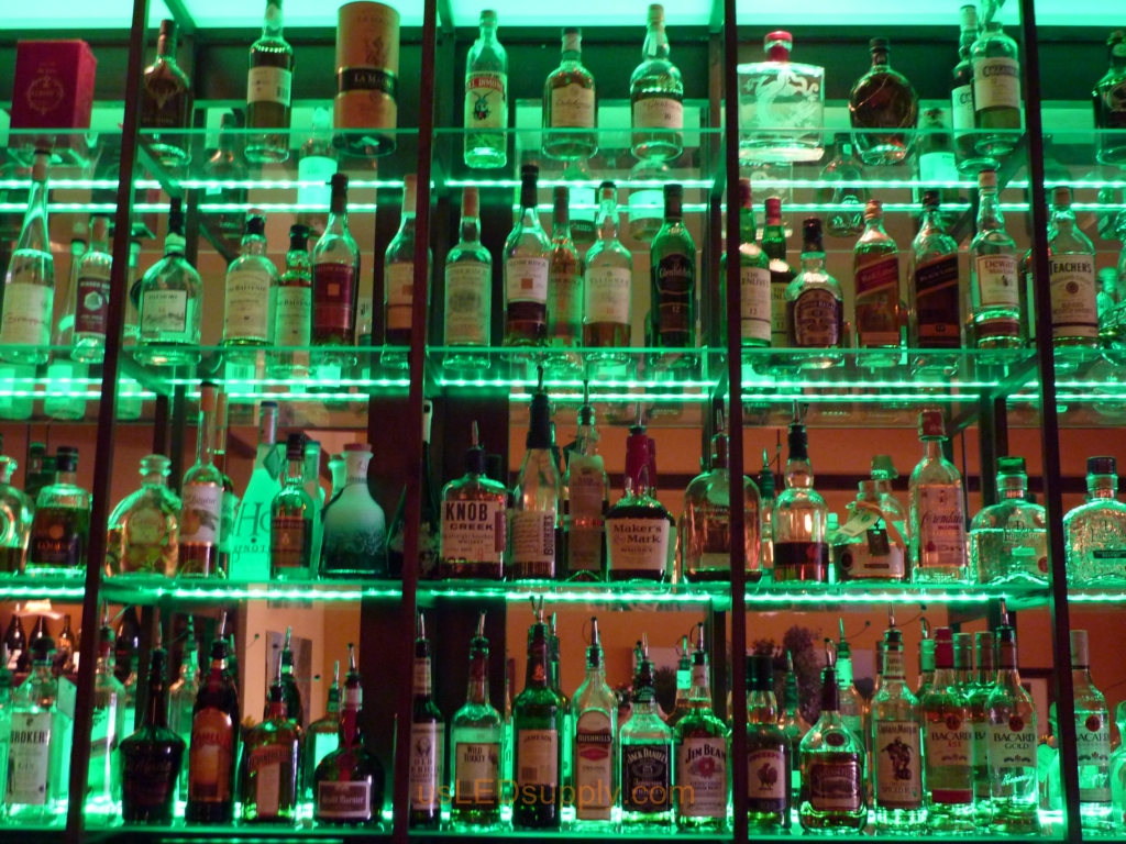 Glass shelving in bar with RGB flexible LED strips behind them makes the glass shelving and bottles glow.