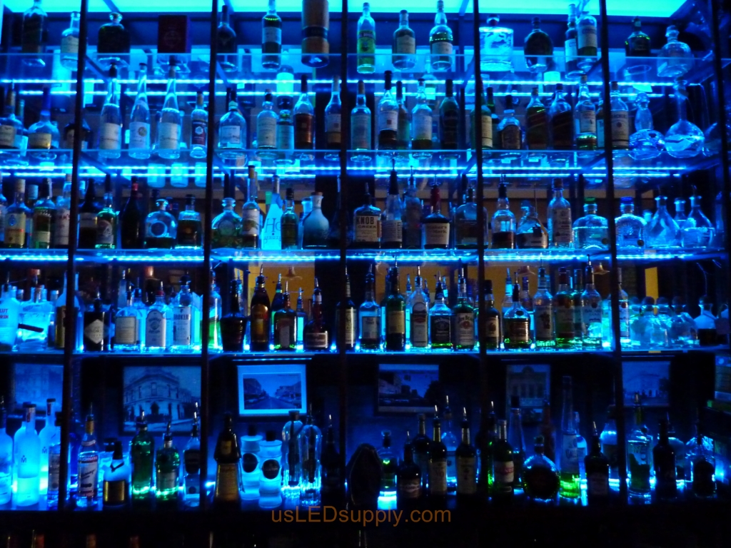 Glass shelving in bar with RGB flexible LED strips behind them makes the glass shelving and bottles glow.