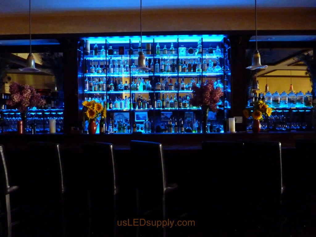 Glass shelving in bar with RGB flexible LED strips behind them makes the glass shelving and bottles glow.
