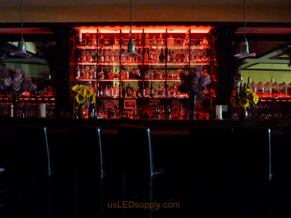 Glass shelving in bar with RGB flexible LED strips behind them makes the glass shelving and bottles glow.