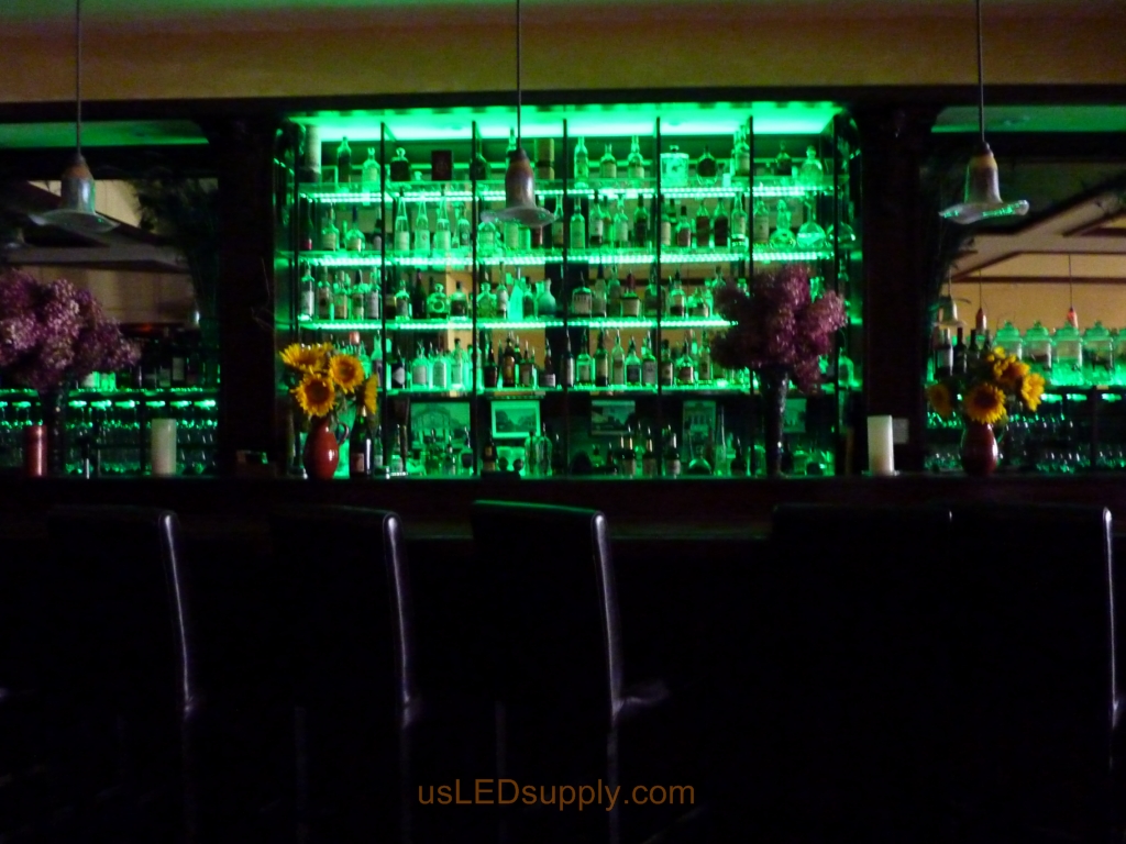 Glass shelving in bar with RGB flexible LED strips behind them makes the glass shelving and bottles glow.