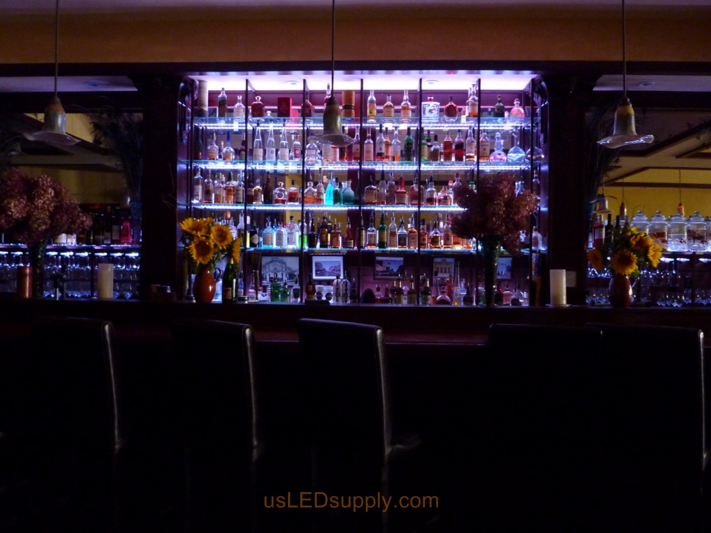 Glass shelving in bar with RGB flexible LED strips behind them makes the glass shelving and bottles glow.