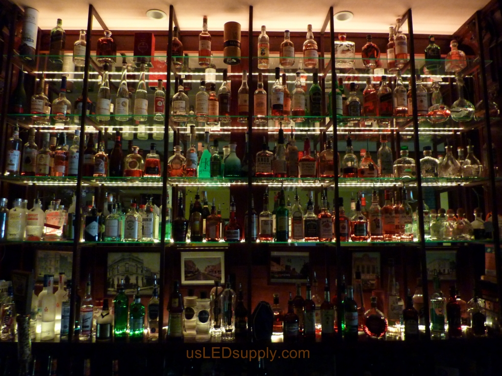 Glass shelving in bar with RGB flexible LED strips behind them makes the glass shelving and bottles glow.