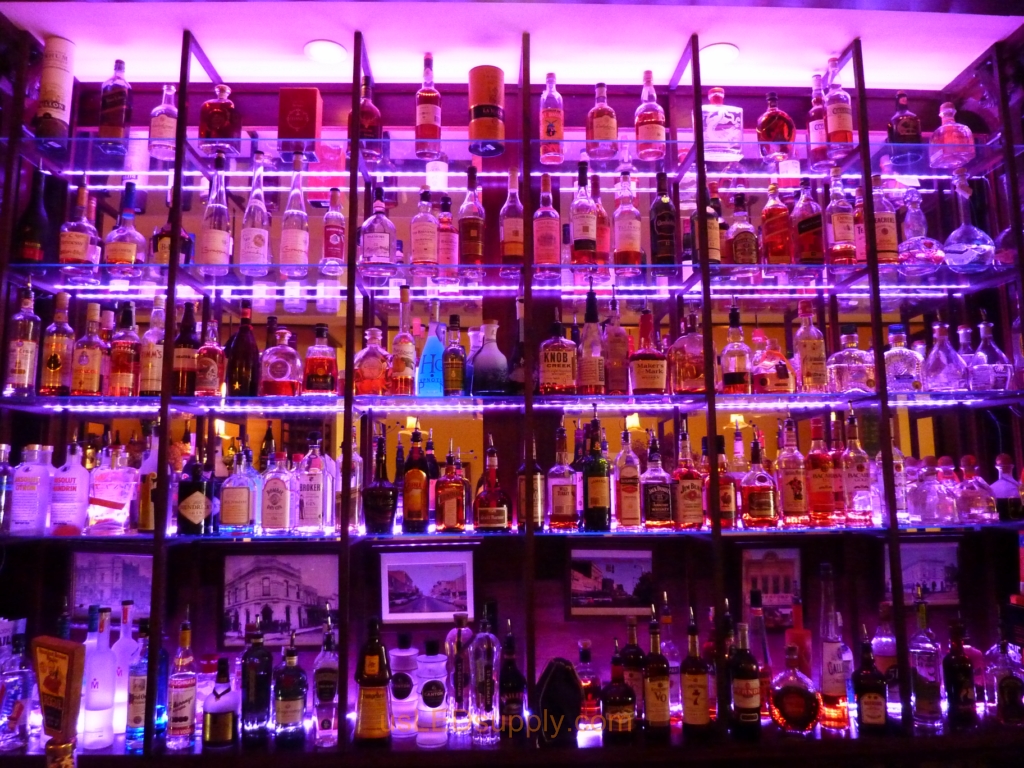 Glass shelving in bar with RGB flexible LED strips behind them makes the glass shelving and bottles glow.