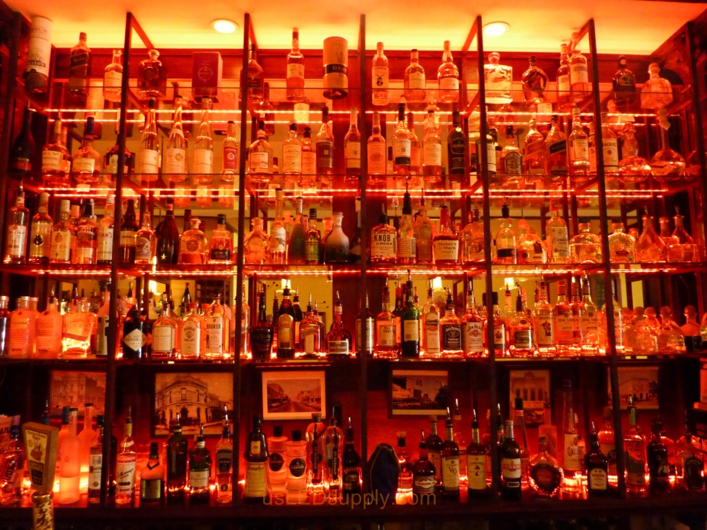 Glass shelving in bar with RGB flexible LED strips behind them makes the glass shelving and bottles glow.