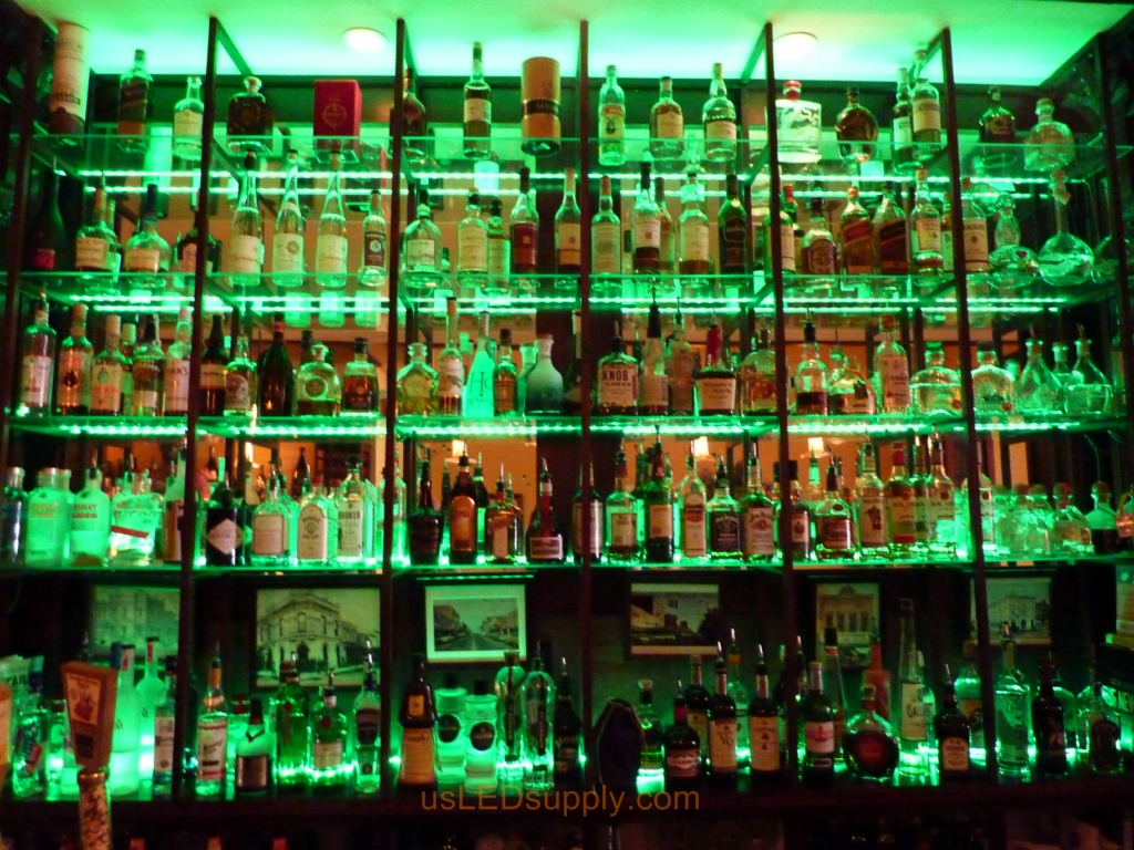Glass shelving in bar with RGB flexible LED strips behind them makes the glass shelving and bottles glow.