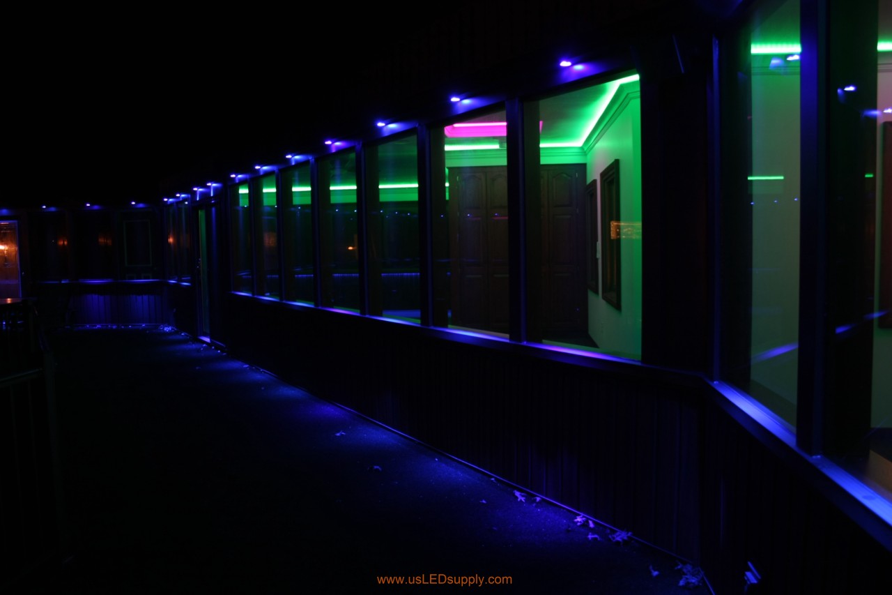 RGB LED puck lights above windows of a glassed in walkway.