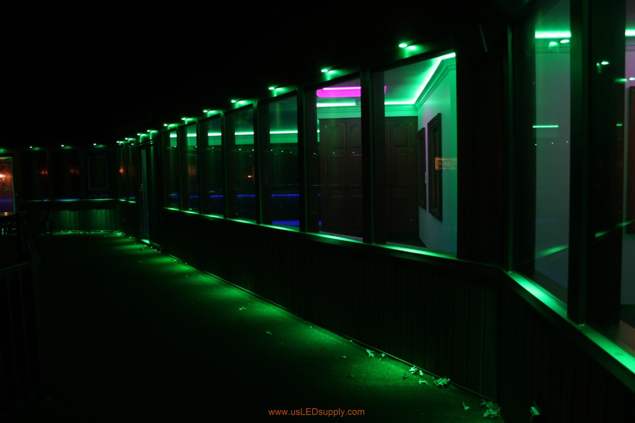 RGB LED puck lights above windows of a glassed in walkway.