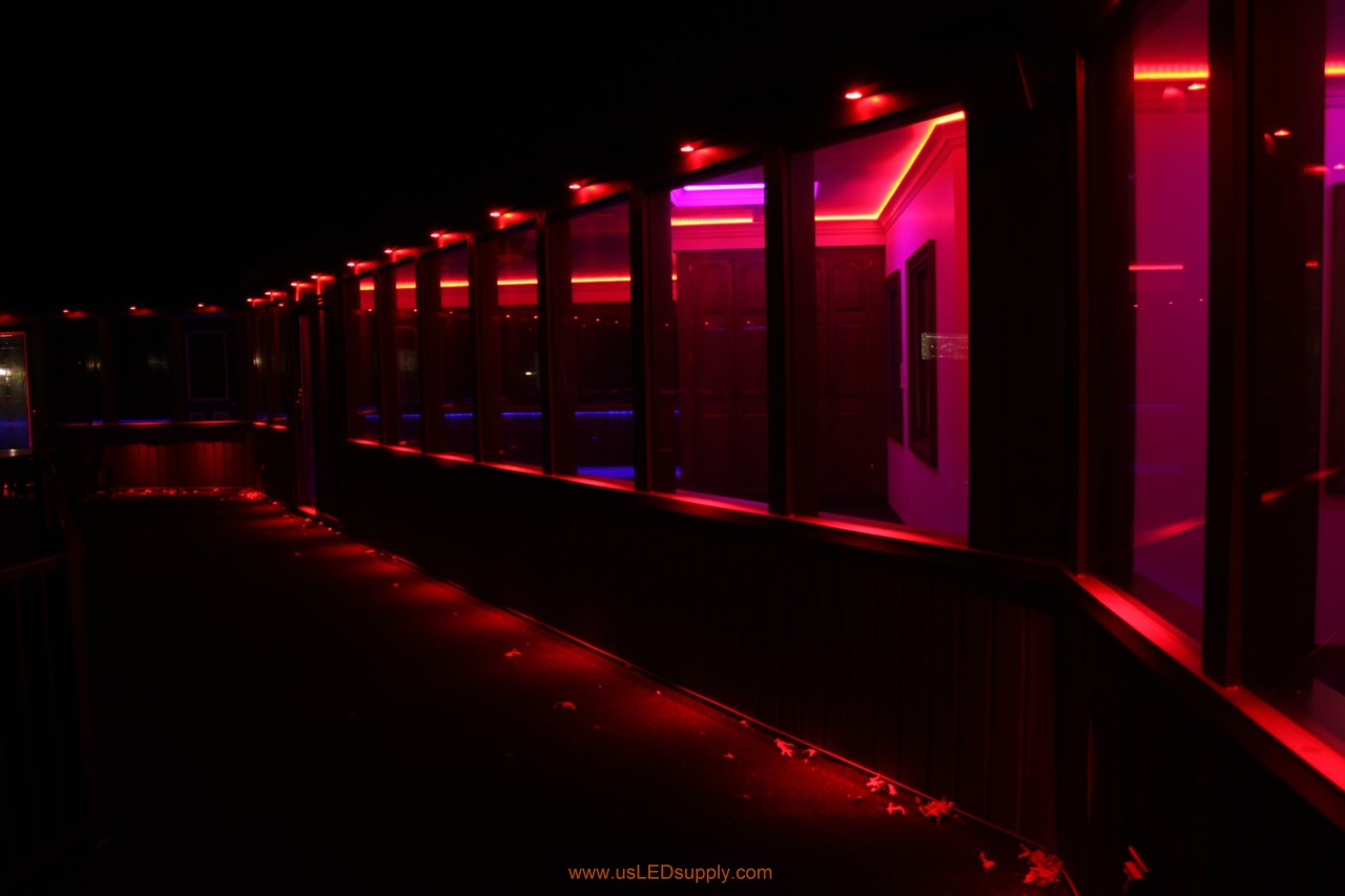 RGB LED puck lights above windows of a glassed in walkway.