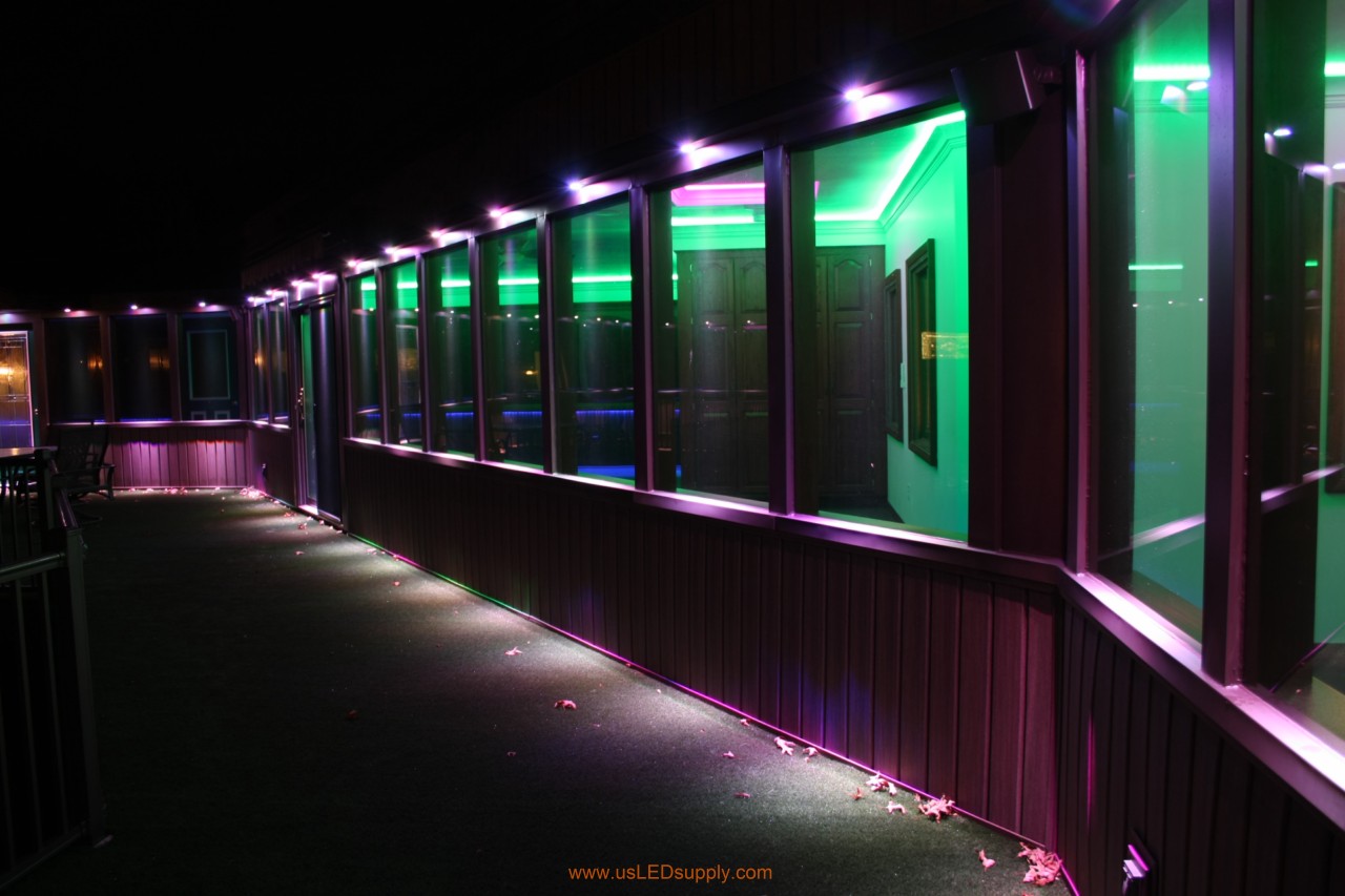 RGB LED puck lights above windows of a glassed in walkway.