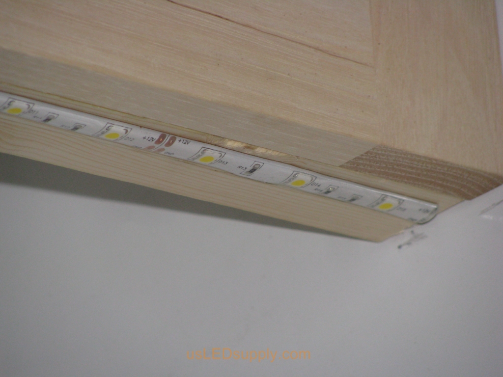 Attaching the flexible LED strip to the bottom of the cabinet using SMD self stick backing.