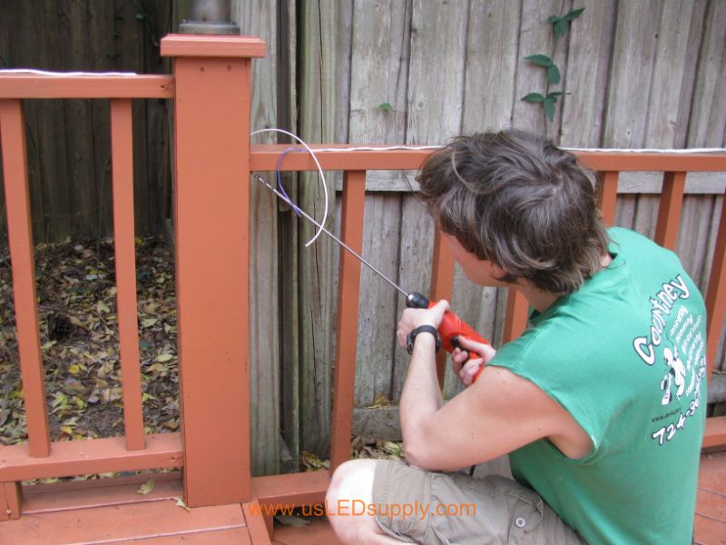 Drilling through a Deck Post in order to run wire through it.